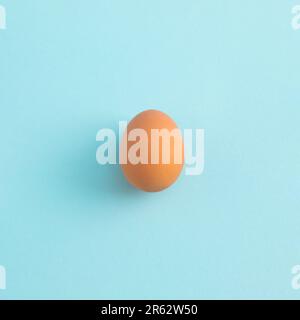 Uncooked egg on pastel blue background. Minimal food concept with copy space. Top view, flat lay. Stock Photo