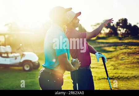Ill show you how to take it home. two friends playing a round of golf out on a golf course. Stock Photo