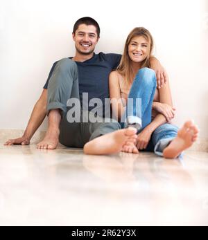 Sharing a relaxed relationship with one another. Happy young couple sitting together and smiling. Stock Photo