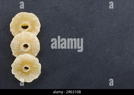 Dried candied pineapple slices photographed overhead on slate with copy space on the side Stock Photo