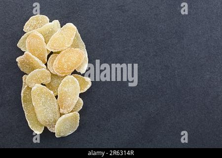 Sweet and spicy candied or crystallized ginger slices photographed overhead on slate with copy space on the side Stock Photo