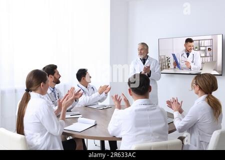 Lecture with online participant. Doctors in meeting room. Using tv for videoconference Stock Photo