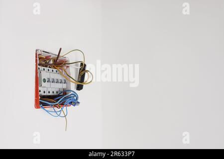 Switchboard with different cables on white wall, space for text. Installation of electrical wiring Stock Photo