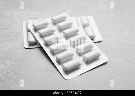 Blisters with chewing gums on light grey table, closeup Stock Photo