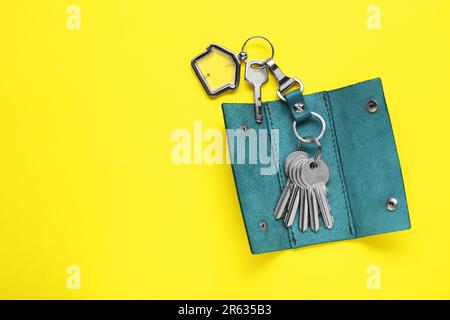 Open leather holder with keys on yellow background, top view. Space for text Stock Photo