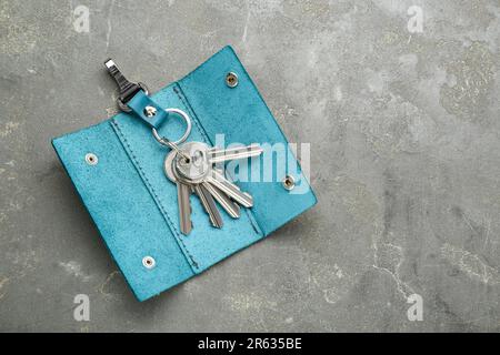 Stylish leather holder with keys on grey textured table, top view. Space for text Stock Photo