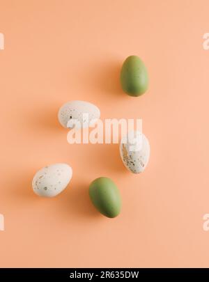 Easter pattern made of white and green eggs on pastel orange background. Minimal Easter holiday composition. Stock Photo