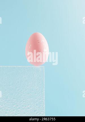 Pink Easter egg on sky blue background. Embossed glass texture background. Minimal festive concept. Abstract Easter card. Copy space. Stock Photo