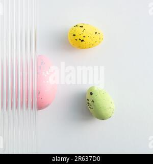 Modern composition made of pastel green and pink Easter eggs on grey background. Embossed glass texture background. Minimal festive concept. Abstract Stock Photo