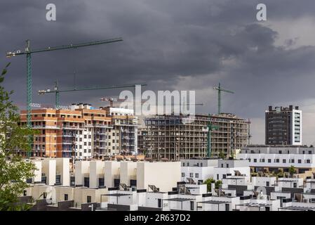 Facades of residential buildings under construction with many cranes on a cloudy day Stock Photo