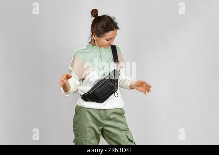 Woman Wearing Crossbody a Black Leather Belt Bag over Grey Background. Handmade Leather Accessories Goods Stock Photo