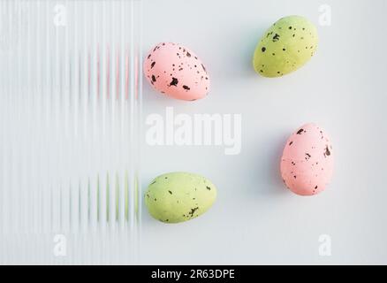 Modern composition made of pastel green and pink Easter eggs on grey background. Embossed glass texture background. Minimal festive concept. Abstract Stock Photo