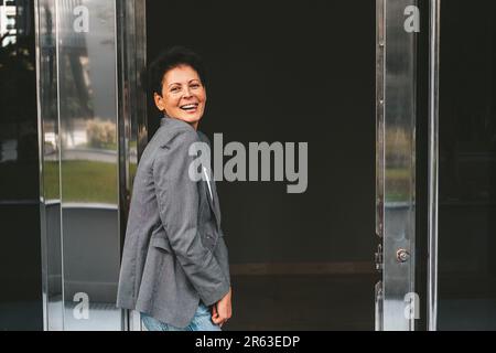 A brunette with a short haircut in modern clothes stands near the business center.  Stock Photo