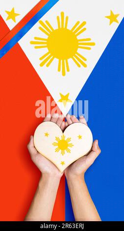 A human hand is holding a heart with the Philippine flag color. Philippines Independence Day concept Stock Photo