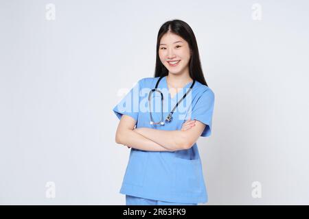 Portrait of smiling woman doctor in blue coat posing with folded arms isolated over white background. Stock Photo