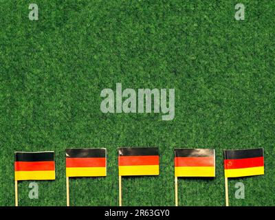 Small German flags on a green grass background with space for text or image Stock Photo