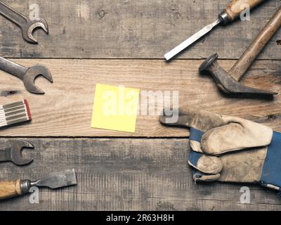 Old used tools with a sticky note on a workbench with space for text Stock Photo