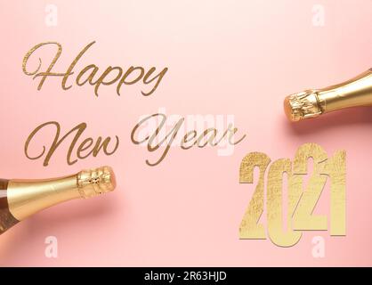 The words Happy New Year with golden 2021 ona pink background with two bottles of champagne, New Year greetings, festive background Stock Photo