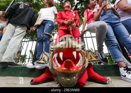 A Yare Dancing Devil rests among the audience. Every year on the ninth Thursday after Holy Thursday the Diablos de Yare dance to celebrate Corpus Christi day Intangible Cultural Heritage of Humanity declared by UNESCO in 2012. Los Diablos de Yare dance through the streets of San Francisco de Yare in Miranda State, staging the triumph of good against evil. It is a tradition that has been going on for 234 years where faithful to the Catholic religion celebrate Corpus Christi Day in Venezuela. Stock Photo