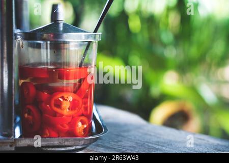Pickled sliced chillies in a glas with tropical sunny setting in an Asian restaurant as an ingredient for spicing up your dish Stock Photo