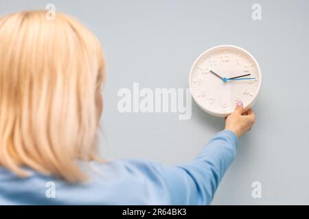 woman hangs a clock on the wall of the room. woman hangs a clock on the wall. Stock Photo