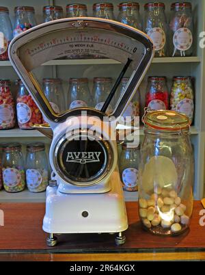 Vintage Avery weighing scales on a traditional sweet shop counter, surrounded by glass jars of confectionery, illustrating historic British retail Stock Photo