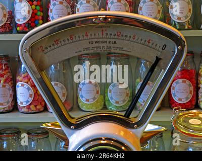 Vintage Avery weighing scales on a traditional sweet shop counter, surrounded by glass jars of confectionery, illustrating historic British retail Stock Photo