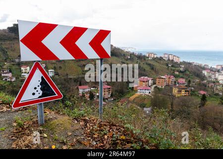 Road signs mounted on a roadside of a mountain road, dangerous turn and Falling rocks Stock Photo