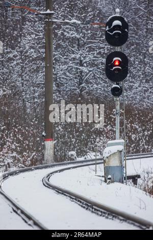 Railway semaphore shows red stop signal. Vertical photo taken on a snowy winter day Stock Photo