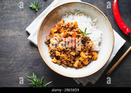 Chili Con Carne in bowl on dark background. Mexican cuisine. chili con carne - minced meat and vegetables stew in tomato sauce. Top view Stock Photo