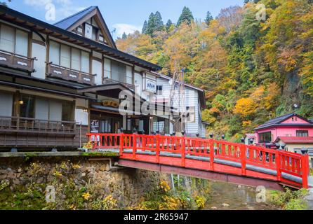 Autumn leaves and a red bridge in Ginzan Onsen Stock Photo