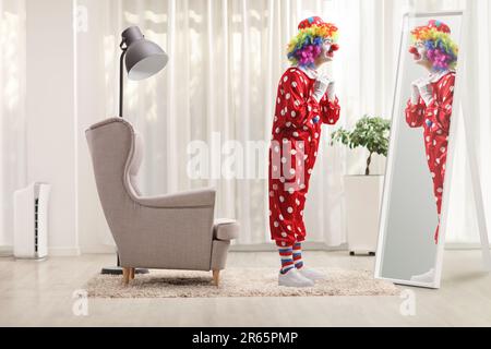 Full length shot of a clown getting ready in front of a mirror at home Stock Photo