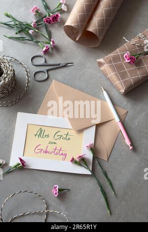 Envelope, greeting card and flowers. Text Alles Gute zum Geburtstag means Happy Birthday. Stock Photo