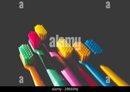 Multicolored bright toothbrushes on a dark background top view flatly. Children's oral hygiene. Morning hygiene, routine and self-care. Set of plastic Stock Photo