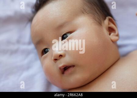 Close-up of Asian newborn baby lying in his cot Stock Photo