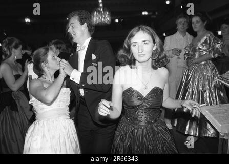 1980s fashion an off the shoulder little black party dress. With the customary cigarette in hand, a lone Sloane Ranger takes to the dance floor to sashay the night away at the annual charity Rose Ball, held in the Grosvenor House Hotel, Park Lane. Mayfair, London, England circa May 1982. HOMER SYKES Stock Photo