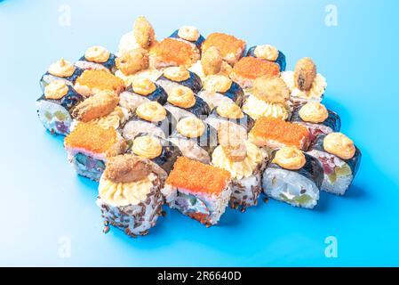 Set of sushi rolls with tobiko, mussels, shrimps, tuna and spicy sauce, on a blue background. High quality photo Stock Photo
