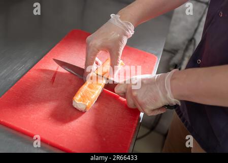 The process of making Japanese sushi. Knife in hand cuts a roll close-up on  a wooden board Stock Photo - Alamy