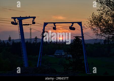 Skilift in front of a sunset over the mountain range of the Rothaargsteig close to Luetzel in Germany. Stock Photo