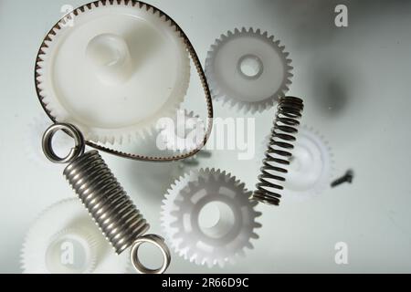 Gear wheels, springs, parts. Plastic gears. Monochrome picture of plastic and metal parts. Creativity from small plastic parts. Printer parts. Stock Photo