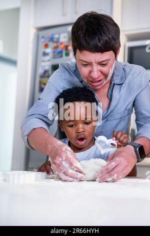 Mother and son baking heart-shape cookies in kitchen at home Stock Photo