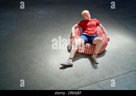 Portrait cool young man relaxing on bean bag chair Stock Photo