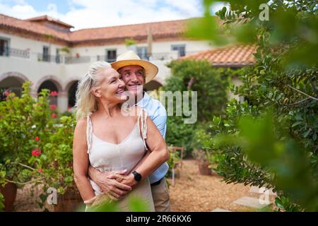 Happy senior couple hugging in garden outside summer villa Stock Photo