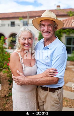 Portrait happy senior couple hugging in villa garden Stock Photo