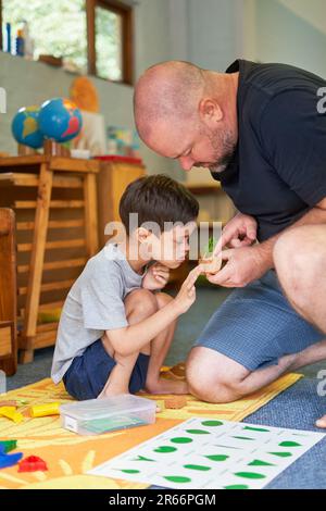 Father teaching son with Down Syndrome about plants at home Stock Photo