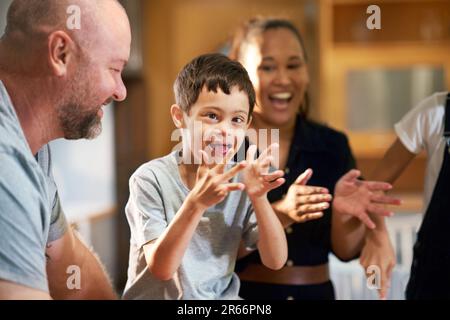 Portrait happy boy with Down Syndrome clapping with family Stock Photo