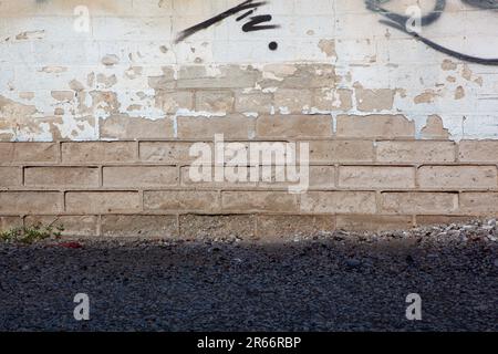 Background of partial painted white brick wall with peeling texture and grass Stock Photo