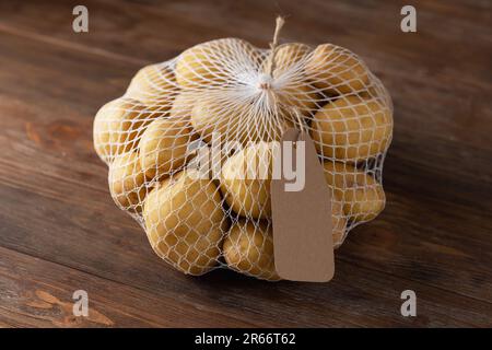 Grid with potatoes on a brown wooden background with an inscription label with empty space Stock Photo