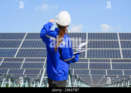 Female engineer worker with solar panels at solar farm Stock Photo