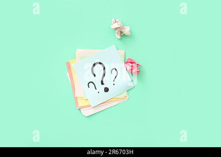 Sticky notes with question marks and crumpled paper on green background Stock Photo